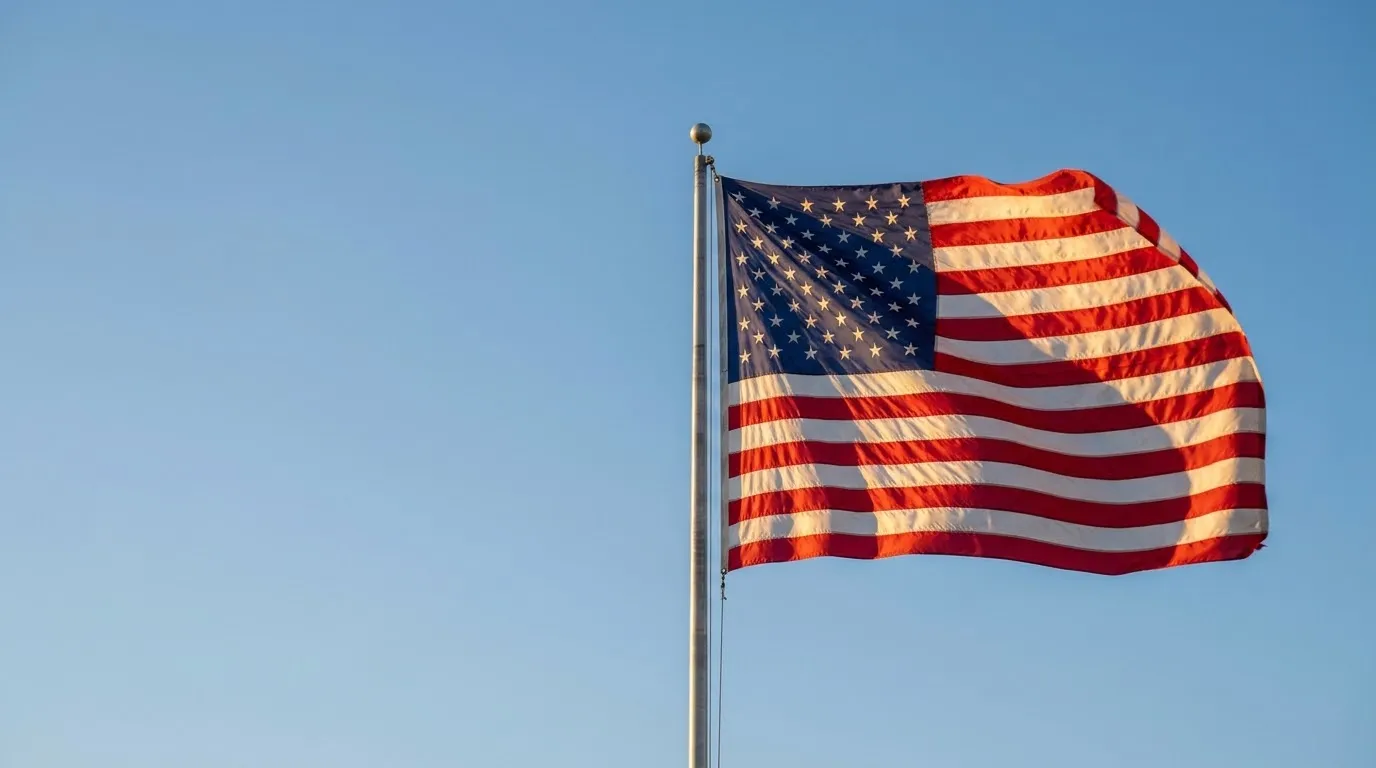 American flag waving against a clear morning blue sky from a residential flagpole